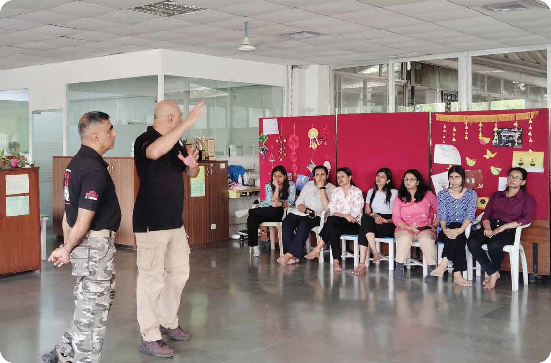 Self-defence training session with instructor demonstrating techniques to a group of women in a classroom setting